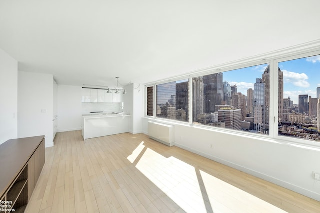 interior space with light wood-type flooring, a city view, baseboards, and an inviting chandelier