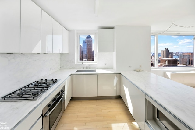 kitchen with decorative backsplash, light stone countertops, a view of city, stainless steel appliances, and white cabinetry