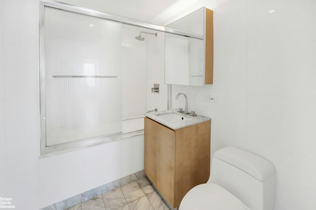 full bath with toilet, a shower with shower door, marble finish floor, vanity, and tile walls