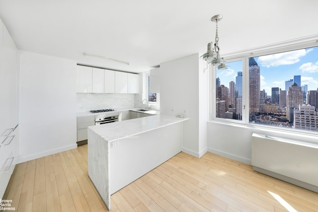 kitchen featuring a peninsula, white cabinets, light countertops, modern cabinets, and decorative light fixtures