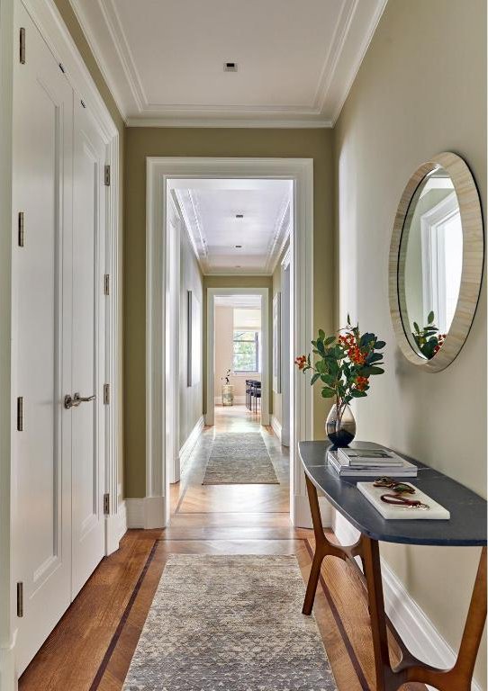 hallway with hardwood / wood-style flooring and ornamental molding