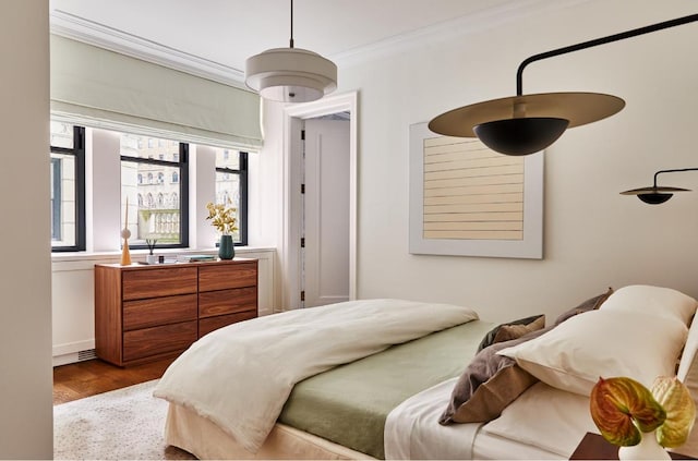 bedroom with ornamental molding and light hardwood / wood-style floors