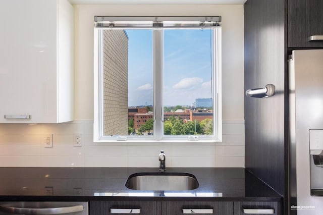 kitchen with stainless steel appliances, dark brown cabinets, backsplash, and sink