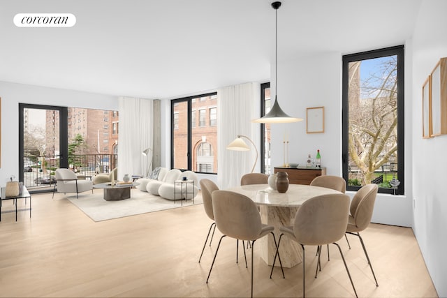 dining room with visible vents, plenty of natural light, light wood-style flooring, and expansive windows