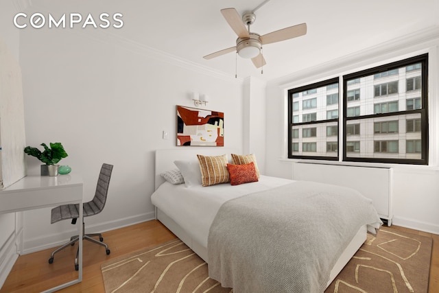 bedroom featuring wood finished floors, baseboards, ornamental molding, and a ceiling fan