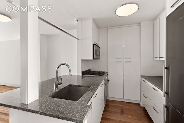 kitchen featuring a sink, white cabinets, stainless steel appliances, modern cabinets, and dark wood-style flooring