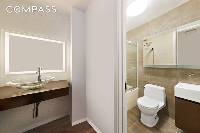 515 E 72nd St Unit 3Klmn, New York City, NY 10021 - bathroom with bath / shower combo with glass door, wood finished floors, vanity, and tile walls
