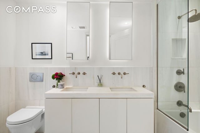 full bath featuring toilet, tile walls, and a sink