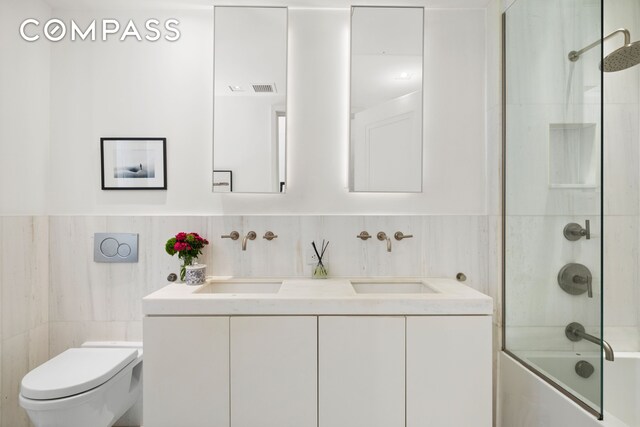 bathroom with a sink, toilet, and tile walls