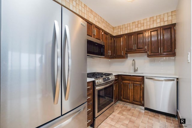 kitchen with appliances with stainless steel finishes, sink, dark brown cabinetry, and backsplash