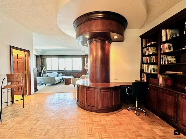 home office with built in desk and light parquet flooring