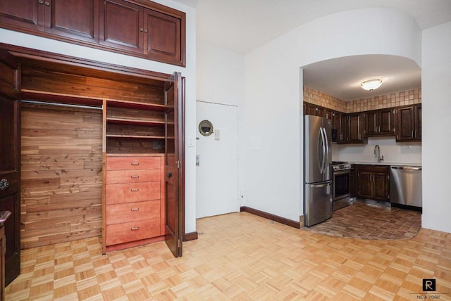 kitchen featuring stainless steel appliances, light parquet flooring, and sink