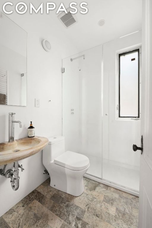 bathroom featuring sink, an enclosed shower, and toilet