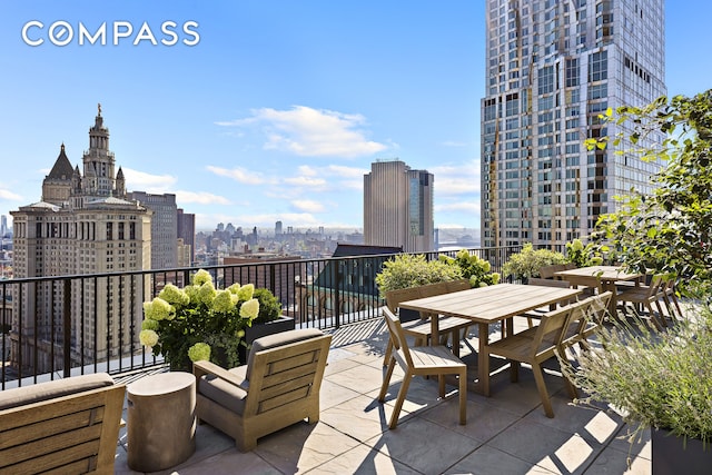 view of patio / terrace with a view of city, a balcony, and outdoor dining space