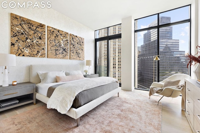 bedroom with a wall of windows and light hardwood / wood-style floors