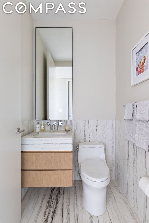 bathroom with vanity, toilet, and tile walls