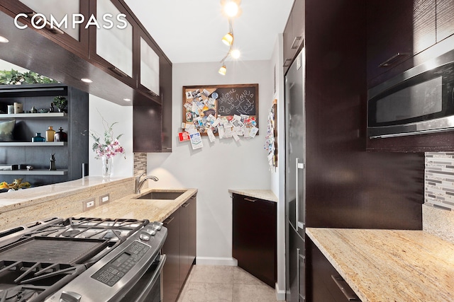 kitchen with stainless steel gas range, a sink, light stone counters, and decorative backsplash