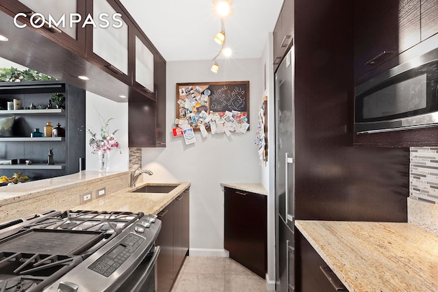 kitchen featuring a sink, gas range, light stone countertops, and dark brown cabinets