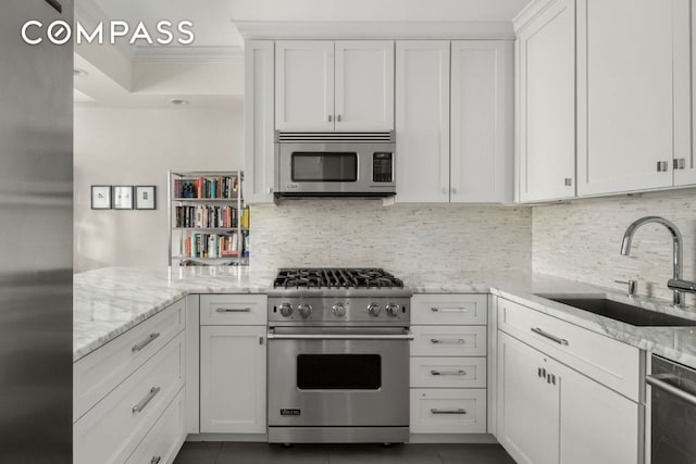 kitchen featuring light stone counters, stainless steel appliances, sink, and white cabinets