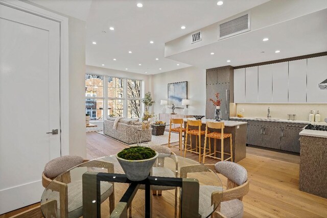 kitchen featuring high end stainless steel range, wall chimney range hood, white cabinets, and a kitchen island with sink