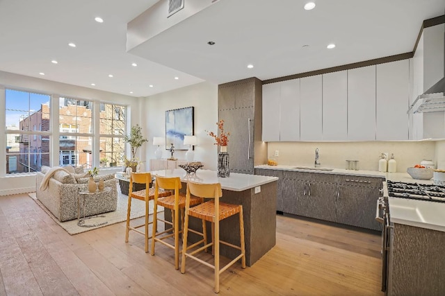 kitchen featuring a center island, white cabinetry, sink, light hardwood / wood-style flooring, and a breakfast bar area