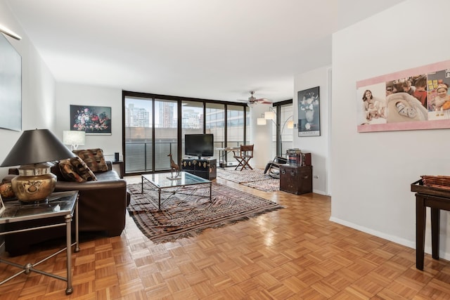 living area featuring floor to ceiling windows, a ceiling fan, and baseboards