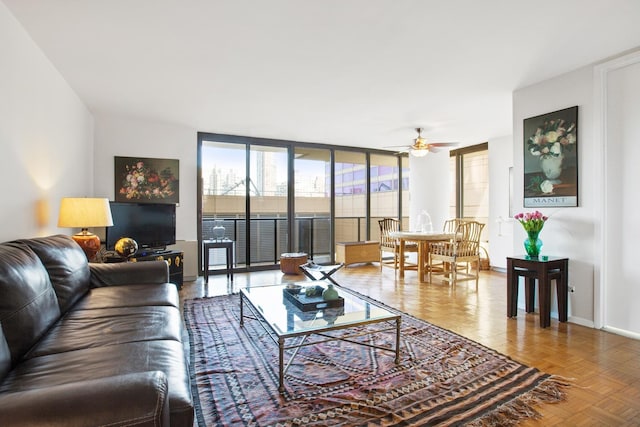 living area featuring a wall of windows, baseboards, and a ceiling fan