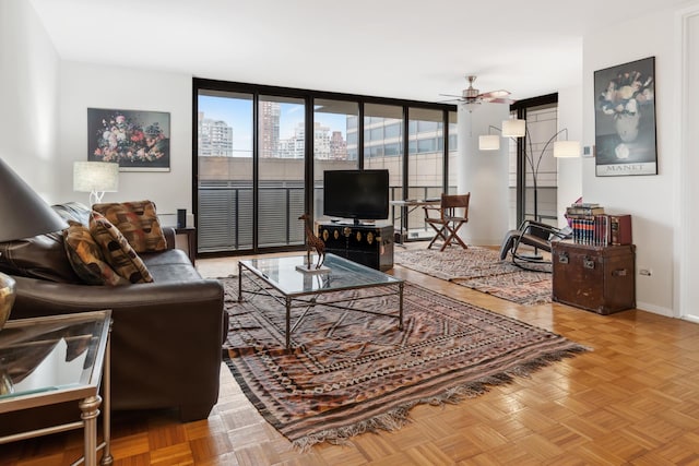 living area featuring baseboards, a wall of windows, and a ceiling fan