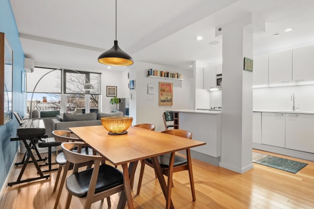 dining space featuring light hardwood / wood-style floors, an AC wall unit, and sink