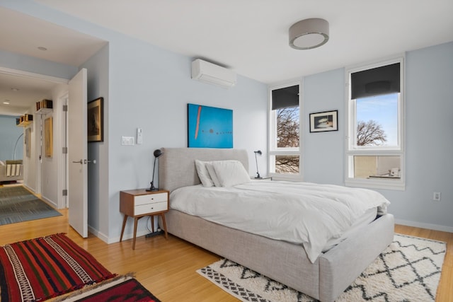 bedroom with light wood-type flooring and a wall mounted air conditioner