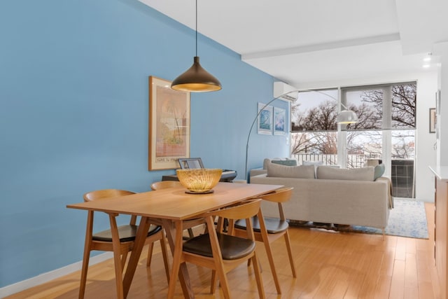 dining area with light hardwood / wood-style flooring and a wall mounted air conditioner