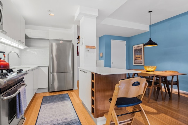 kitchen with pendant lighting, decorative backsplash, sink, appliances with stainless steel finishes, and white cabinets