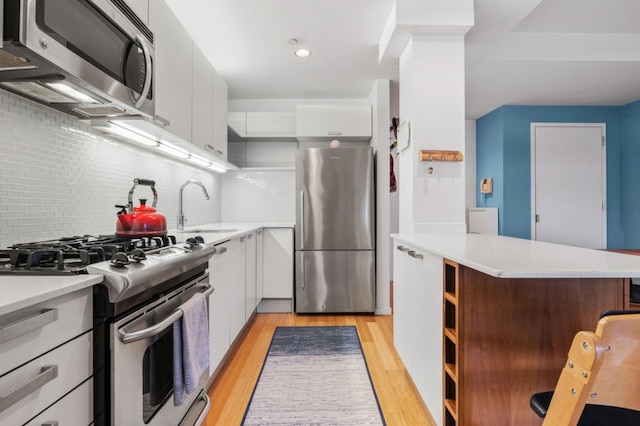 kitchen with decorative backsplash, sink, white cabinetry, light hardwood / wood-style flooring, and stainless steel appliances