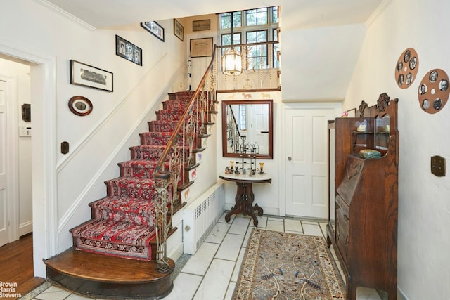 entrance foyer with light tile patterned floors, crown molding, and radiator