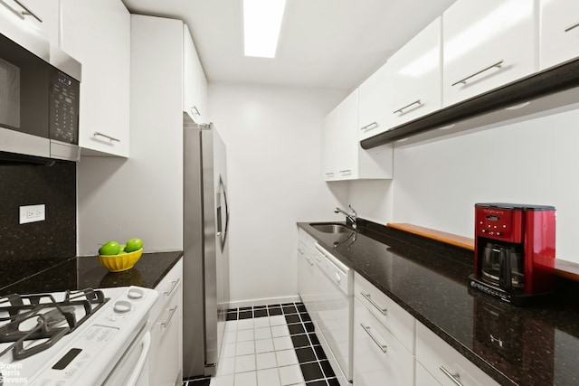 kitchen featuring tile patterned floors, sink, white cabinetry, stainless steel appliances, and dark stone counters