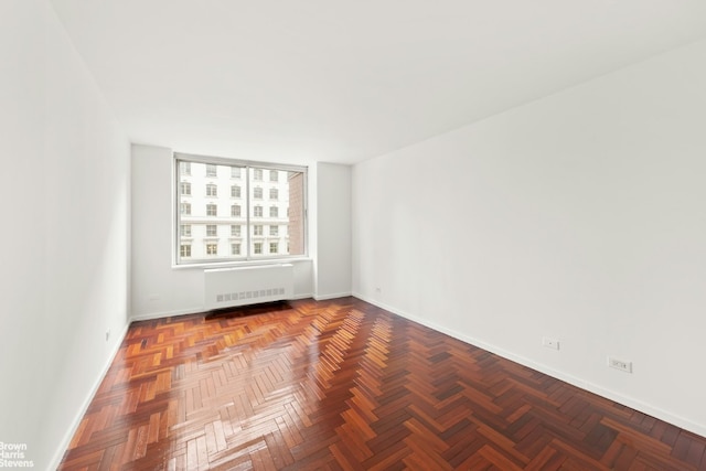 spare room featuring parquet flooring and radiator heating unit