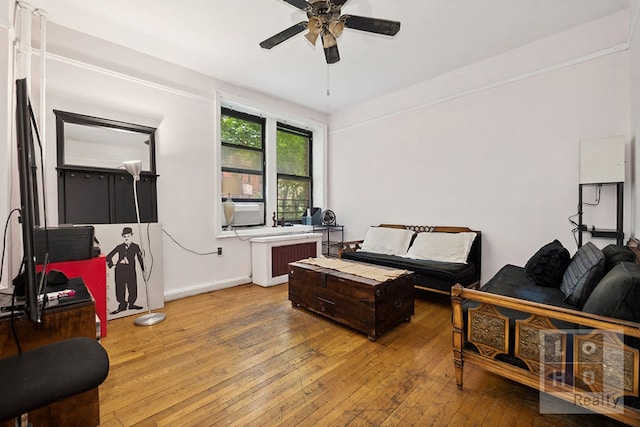 living area featuring a ceiling fan, baseboards, cooling unit, radiator, and hardwood / wood-style floors