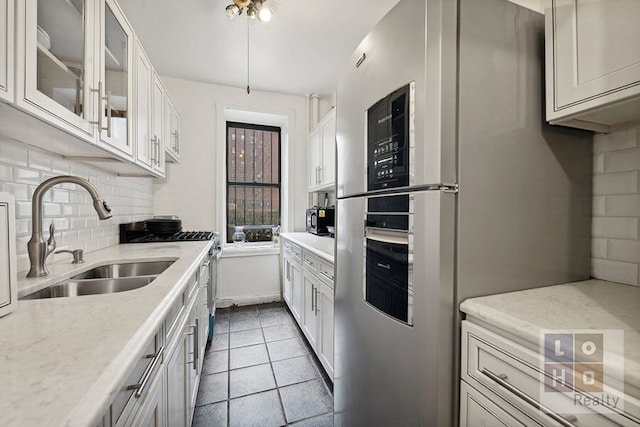 kitchen with sink, white cabinetry, stainless steel appliances, tasteful backsplash, and light tile patterned flooring