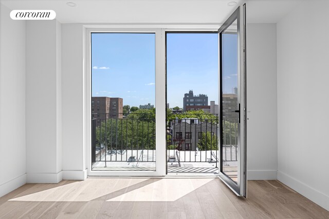 doorway to outside featuring a city view, visible vents, baseboards, floor to ceiling windows, and light wood finished floors