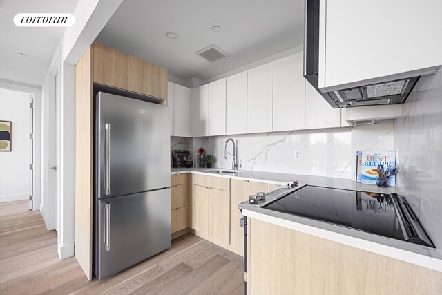 kitchen featuring light countertops, visible vents, freestanding refrigerator, a sink, and modern cabinets