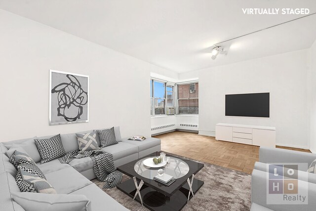 living room with parquet floors, radiator heating unit, and rail lighting