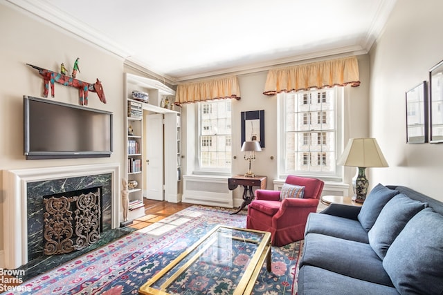 living room featuring wood-type flooring, crown molding, a premium fireplace, and a healthy amount of sunlight