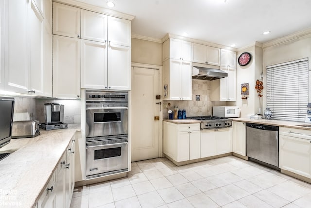 kitchen with light stone countertops, appliances with stainless steel finishes, tasteful backsplash, ornamental molding, and light tile patterned floors