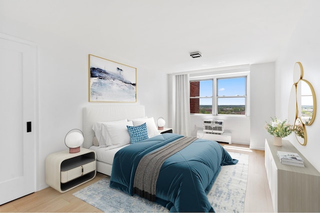 bedroom with light wood-style floors and a wall mounted air conditioner