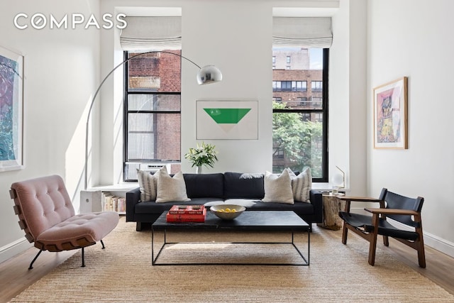 living area featuring light wood-type flooring, a towering ceiling, and baseboards