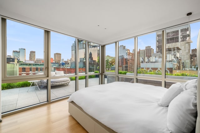 bedroom featuring a view of city, multiple windows, and wood finished floors