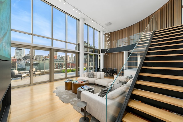 living room featuring wood finished floors, stairs, floor to ceiling windows, a view of city, and track lighting