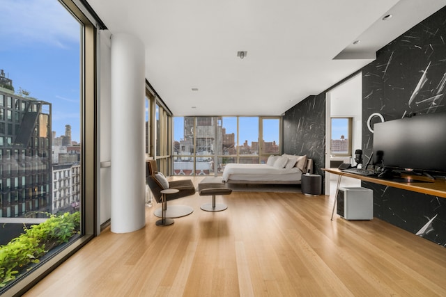 bedroom featuring multiple windows, light hardwood / wood-style floors, and a wall of windows