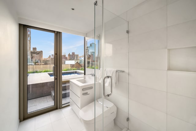 bathroom with tile patterned floors, toilet, sink, tile walls, and a shower with door