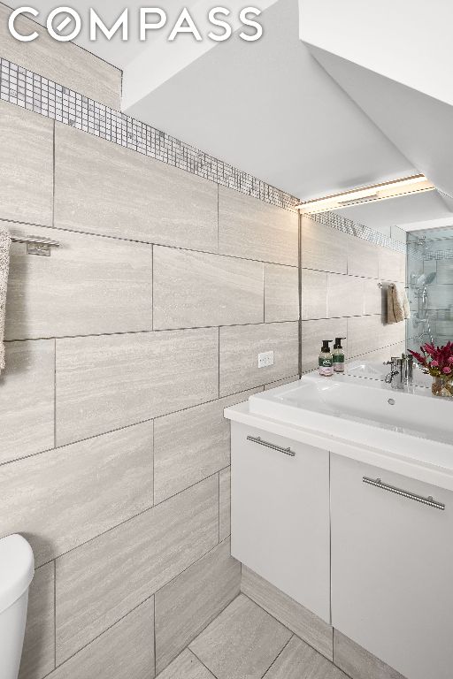 bathroom with tile patterned floors, vanity, toilet, and tile walls